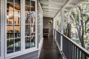 - une terrasse couverte avec de grandes fenêtres et une chaise dans l'établissement Yallingup Lodge Spa Retreat, à Yallingup