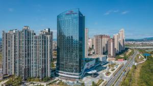 a tall glass building in the middle of a city at Crowne Plaza Quanzhou Riverview, an IHG Hotel in Quanzhou