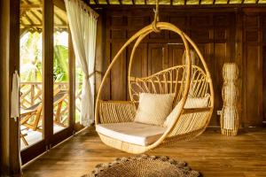 a porch with a swinging chair in a room at Tanah Damai Hotel in Nusa Penida