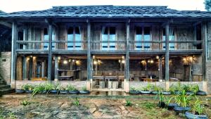un bâtiment en bois avec des tables et des plantes devant lui dans l'établissement A Su Homestay Mù Cang Chải, à Mù Cang Chải