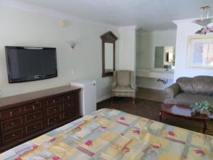 1 dormitorio con 1 cama, TV y silla en Azusa Inn, en La Puente