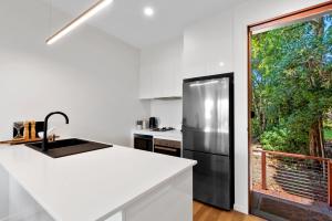 eine Küche mit einem schwarzen Kühlschrank und einem Fenster in der Unterkunft The Ridge at Maleny 1 Bedroom Villa with Spa in Maleny