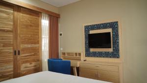 um quarto de hotel com uma cama e uma televisão em Aldeoz Residence Kuta em Kuta