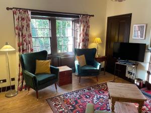 a living room with two chairs and a television at Harmony Cottage - Harmony Gardens in Melrose