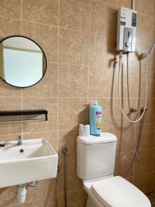 a bathroom with a toilet and a sink and a mirror at Simfoni Beliza Apartment with Roof Top Pool by Vintage in Kuah