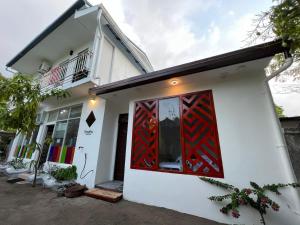 Uma casa branca com uma porta vermelha. em Raalhu Dhangethi em Dhangethi