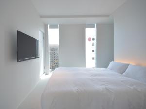 a white bedroom with a bed and a flat screen tv at Carta Hotel Kyoto Gion in Kyoto