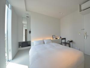 a white bedroom with a white bed and a window at Carta Hotel Kyoto Gion in Kyoto