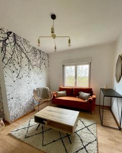 ein Wohnzimmer mit einem roten Sofa und einem Tisch in der Unterkunft LA VILLA DEKO - Appart2 - Université et Hôpital in Beuvry