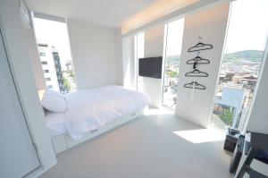 a white bedroom with a bed and large windows at Carta Hotel Kyoto Gion in Kyoto