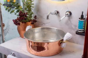 a copper bucket sitting on a counter next to a sink at ARCHONTARIKI Historic Boutique Hotel in Ioannina