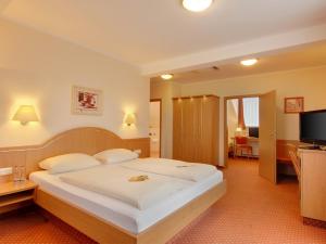 a bedroom with a large white bed in a room at Hotel Kriemhild am Hirschgarten in Munich