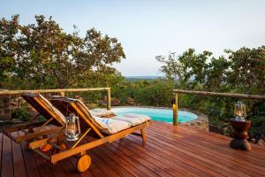 a deck with chairs next to a swimming pool at Elephants Crossing in Welgevonden Game Reserve