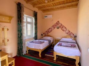 a bedroom with two beds and a window at Khiva Amir Tora B&B in Khiva