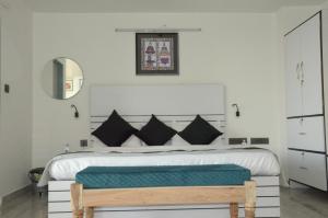 1 dormitorio con 1 cama blanca grande y banco de madera en Divy Villa, en Jaipur 30 fotos más