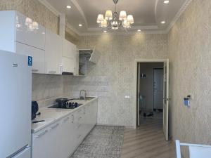 a kitchen with white cabinets and a chandelier at Lovely house in the city center in Bishkek