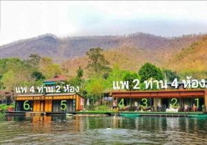 ein Gebäude auf dem Wasser mit Bergen im Hintergrund in der Unterkunft Baan Krupong in Ban Tha Thong Mon