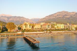 a beach with a pier in the water with buildings at Fame Residence Kemer & Spa in Kemer