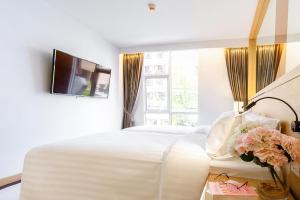 ein Schlafzimmer mit einem großen weißen Bett und einem TV in der Unterkunft FX HOTEL NANA in Bangkok