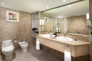 a bathroom with a toilet a sink and a mirror at Beach Rotana - Abu Dhabi in Abu Dhabi