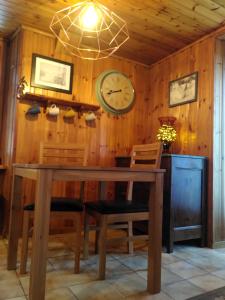 a dining room with a table and a clock on the wall at À Flanc de Montagne in Le Trétien