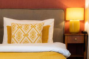 a bedroom with a bed with a yellow pillow and a lamp at Der Schlosswirt zu Anif - Biedermeierhotel und Restaurant in Anif