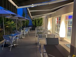 a row of tables and chairs with umbrellas on a patio at Hôtel Gardenia Bordeaux Est in Yvrac +20 photos