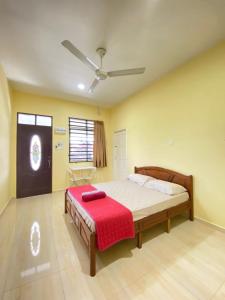 a bedroom with a bed with a red blanket on it at TWIN ROOMSTAY in Kuala Terengganu
