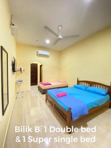 a bedroom with a large bed with blue sheets at TWIN ROOMSTAY in Kuala Terengganu