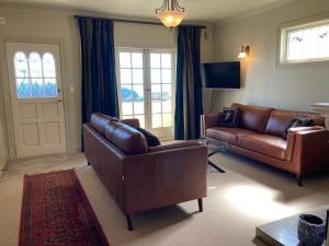 a living room with brown leather furniture and a door at Beachfront Villa in Napier