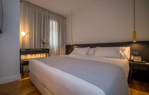a hotel room with a bed and two lamps at Hotel Boutique Loriente in Ribadeo