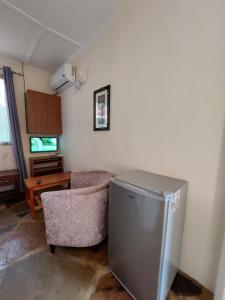 uma sala de estar com uma cadeira, uma mesa e um frigorífico em Amarossi Rhino-Studio Terrace Apartment,Mtwapa em Mtwapa