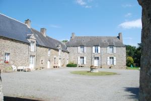 un grand bâtiment en pierre avec une grande cour dans l'établissement Maison charmante à Jugon-les-Lacs avec jardin, à Jugon Les Lacs