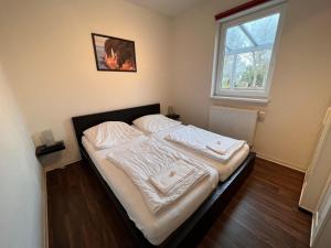 Schlafzimmer mit einem Bett mit weißer Bettwäsche und einem Fenster in der Unterkunft Leuchtfeuer Fewo "Kimberly" in Börgerende-Rethwisch