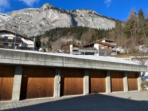 a building with wooden doors with a mountain in the background at Spacious apartment up to 6 people in Flims in Flims