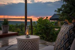 a candle on a table with a view of the sunset at Elephants Crossing in Welgevonden Game Reserve