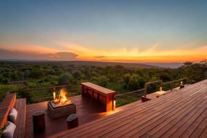 a fireplace on a deck with a sunset in the background at Elephants Crossing in Welgevonden Game Reserve