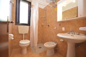La salle de bains est pourvue de toilettes, d'un lavabo et d'un miroir. dans l'établissement Appartamenti Nasse, à Bibione