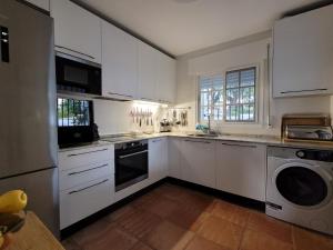 a kitchen with white cabinets and a washer and dryer at Chalet con piscina a 300 m del mar in Chiclana de la Frontera