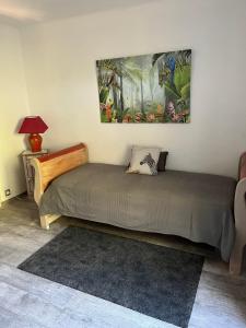 a bed in a room with a painting on the wall at Le Mas du Ruisseau in Bellegarde