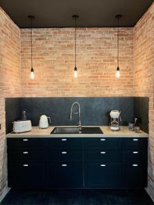 - une cuisine avec un évier et un mur en briques dans l'établissement The Loft, by So & Dam’s, à Thonon-les-Bains