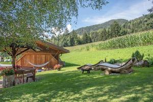 a yard with a hammock and a wooden house at Oberglarzhof App Kirsch in Villnoss