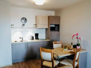 uma cozinha com mesa e cadeiras e uma pequena cozinha com mesa em Domitys Les Raisins Bleus em Villiers-sur-Marne