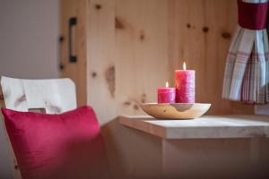 zwei Kerzen auf einem Tisch neben einem Stuhl in der Unterkunft Oberglarzhof App Zirbel in Villnöß