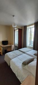 A bed or beds in a room at Logis Hotel Belle-Vue