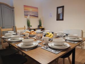 uma mesa de madeira com pratos e tigelas de comida em Large 5 bed town-centre home close to the beach, sleeps 9 em Aberystwyth