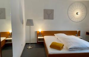 ein Schlafzimmer mit einem Bett mit weißer Bettwäsche und einem gelben Kissen in der Unterkunft Hotel Jägerhof in Coesfeld