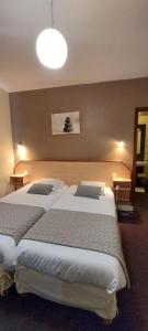 A bed or beds in a room at Logis Hotel Belle-Vue