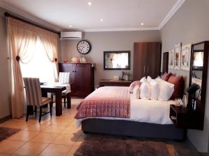 um quarto com uma cama, uma secretária e uma mesa em The Village Inn em Polokwane