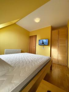 a bedroom with a bed and a tv on the wall at Apartma Idila in Zreče